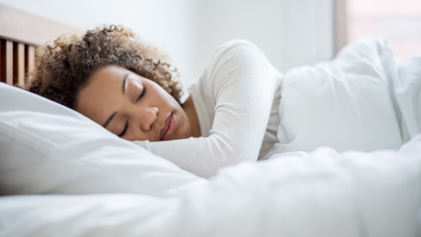 A hot sleeper woman resting comfortably under a breathable duvet cover