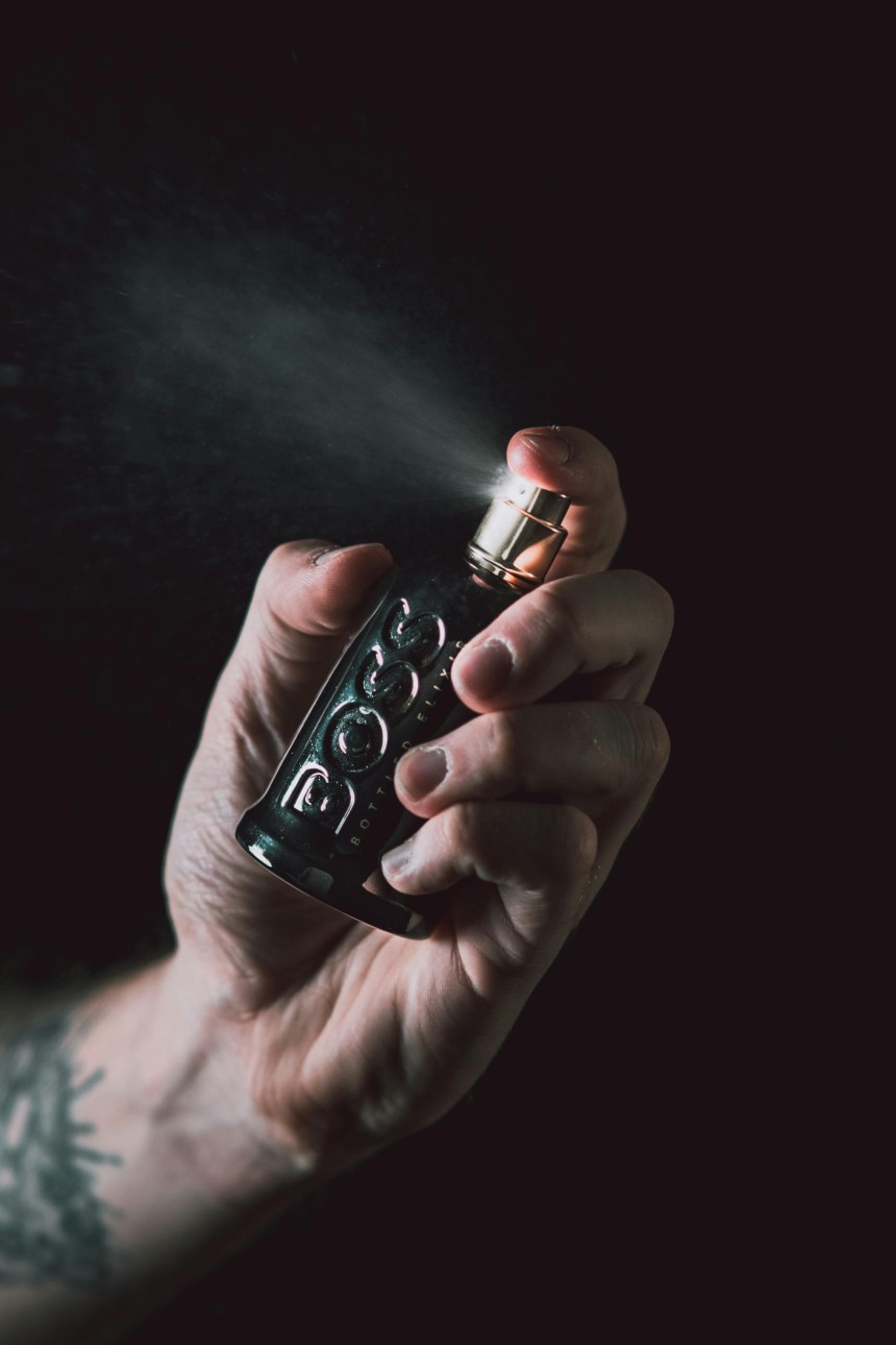 Close-up of a hand spraying a luxury black perfume bottle, symbolizing personal style and fragrance personality