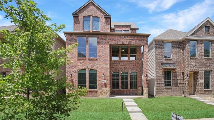 Modern single-story brick home with a two-car garage, well-maintained lawn, and a welcoming front porch at sunset