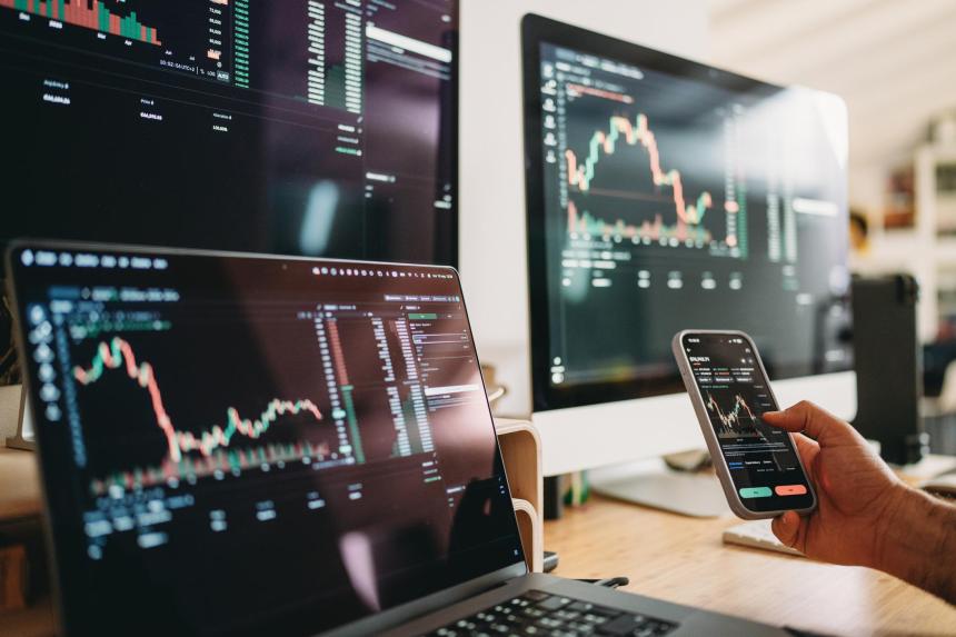 Crypto trading charts on computer monitors, laptop, and smartphone displaying realtime market data